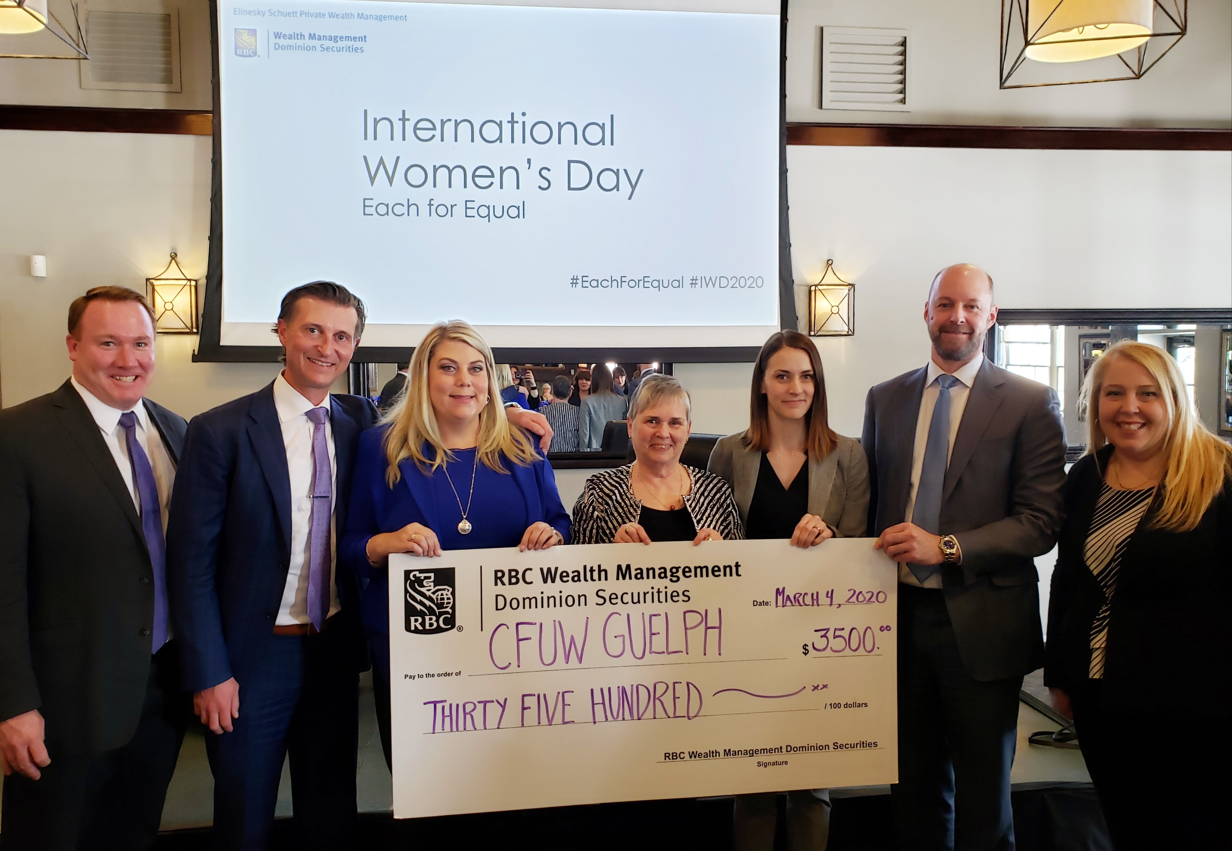 Group of business people holding a large cheque.