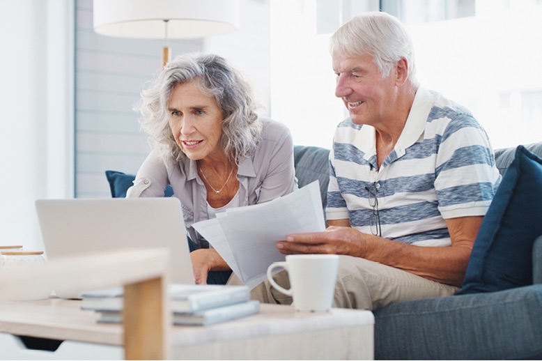 senior-couple-going-through-paperwork-on-sofa-at-home-in-page