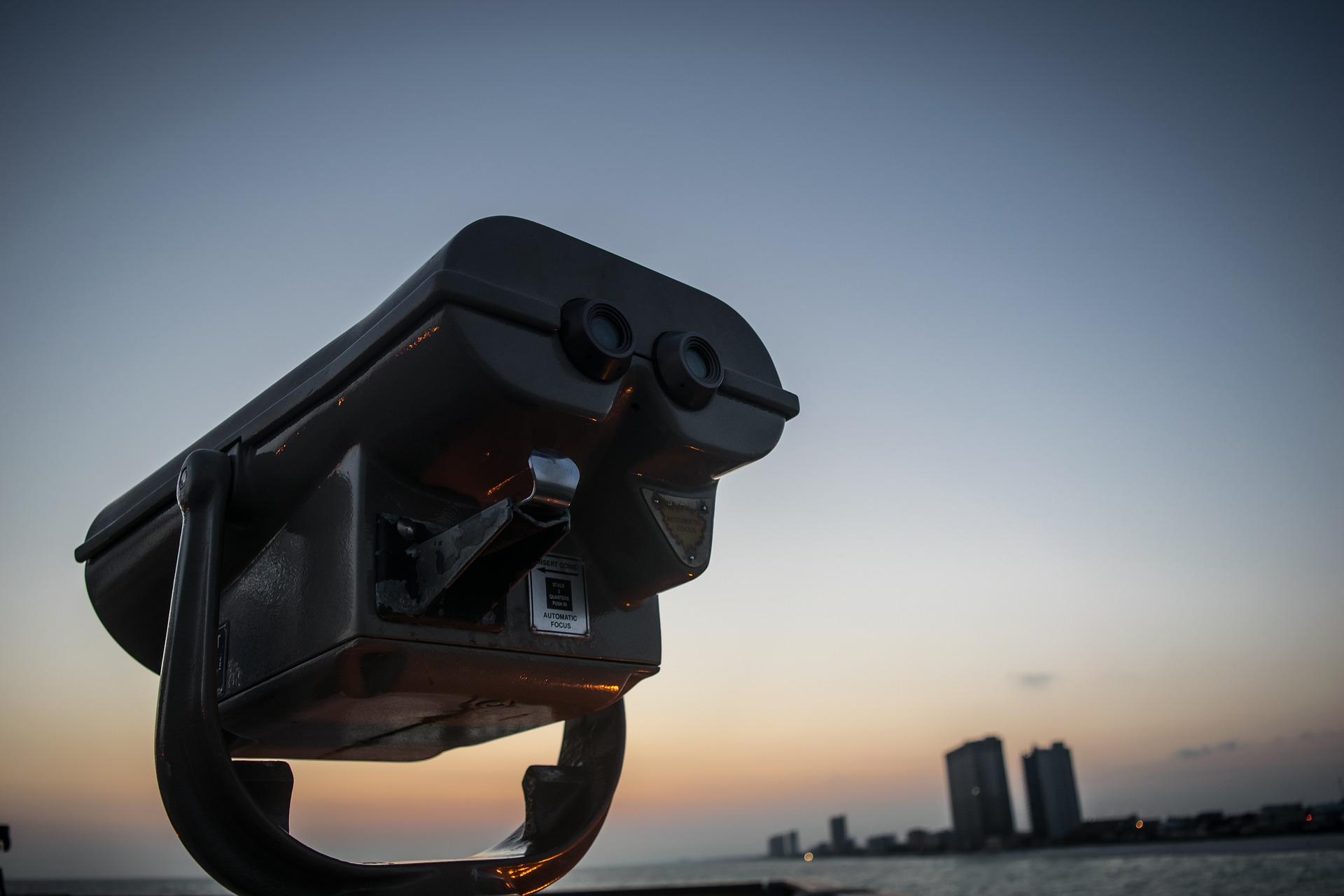 Binoculars overlooking water and a cityscape.