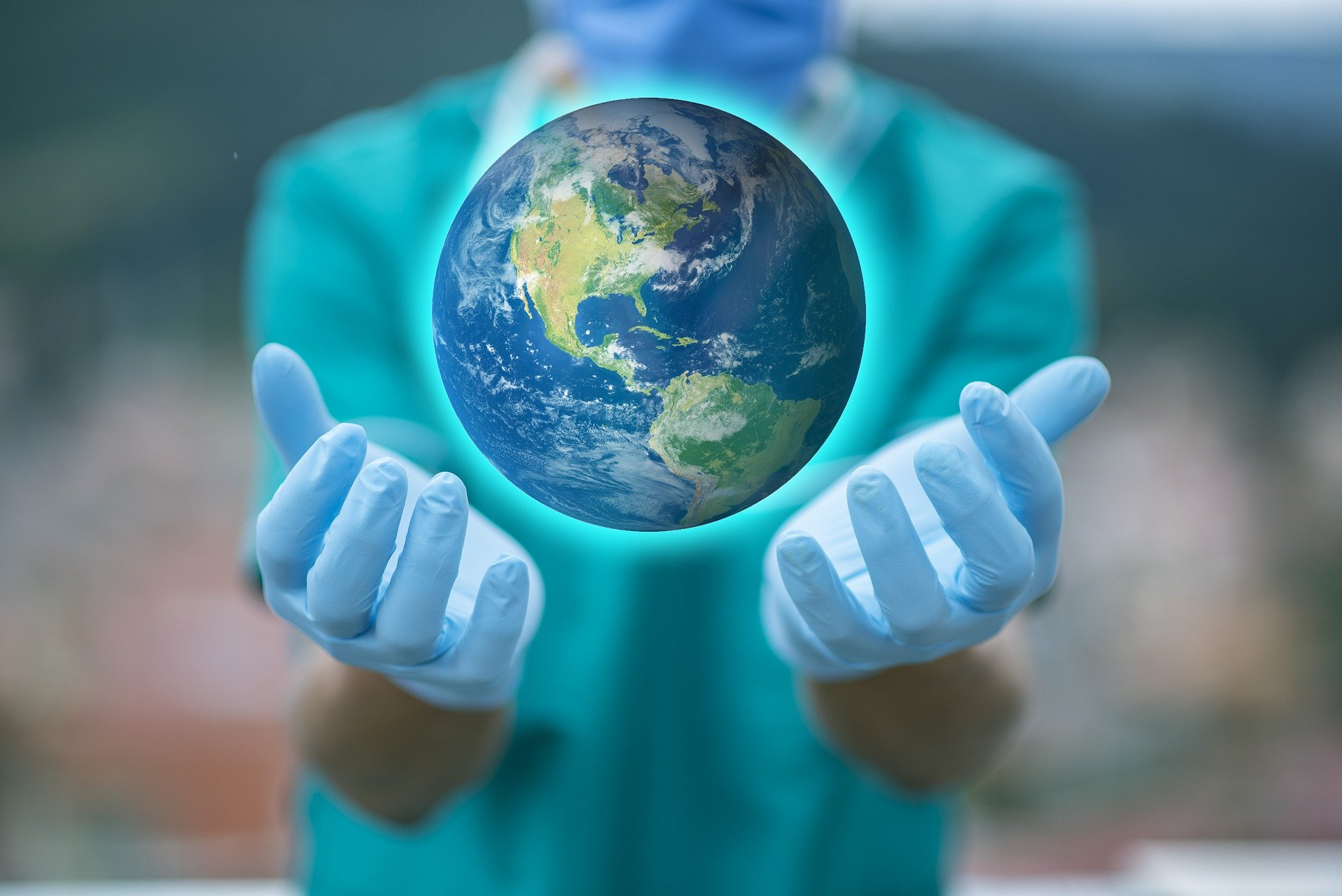 Healthcare professional wearing PPE holding their hands out. Above their hands is a floating picture of a globe.