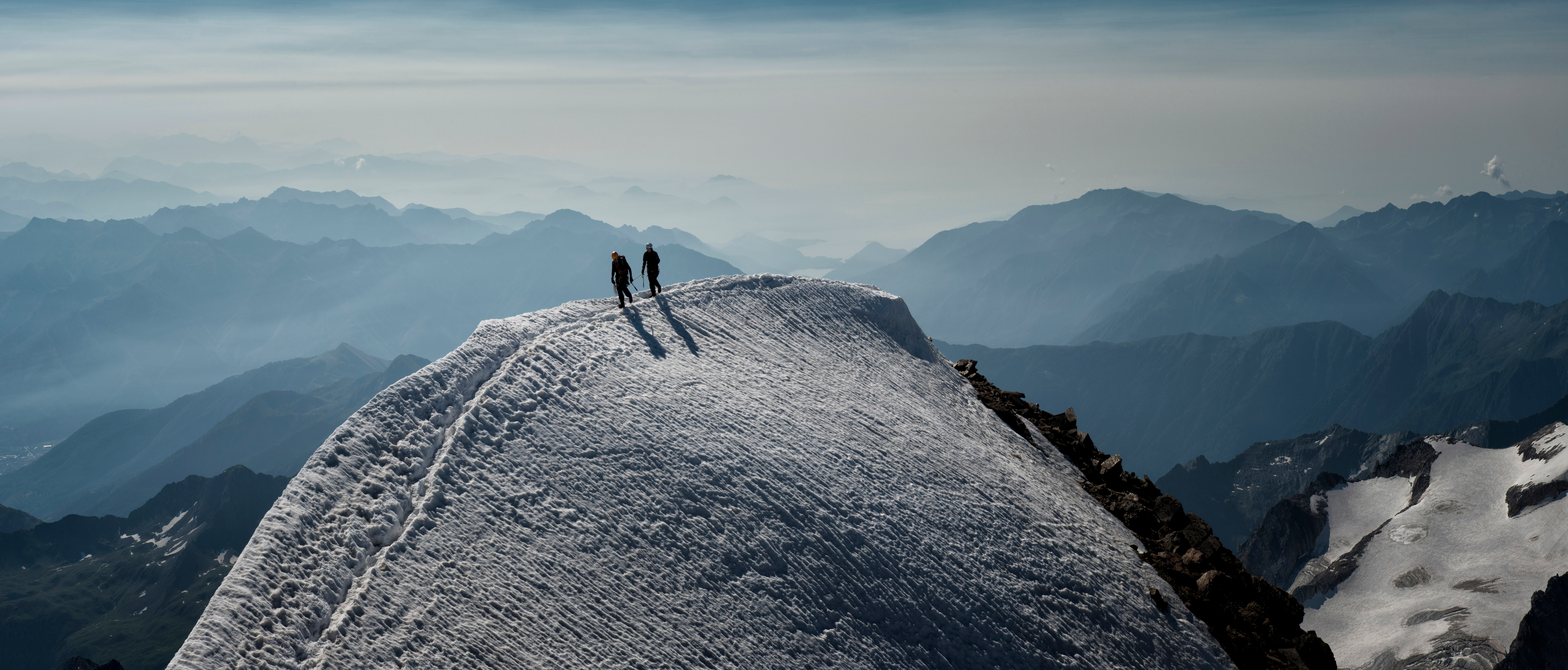 Two people at the crest of a snow mountain