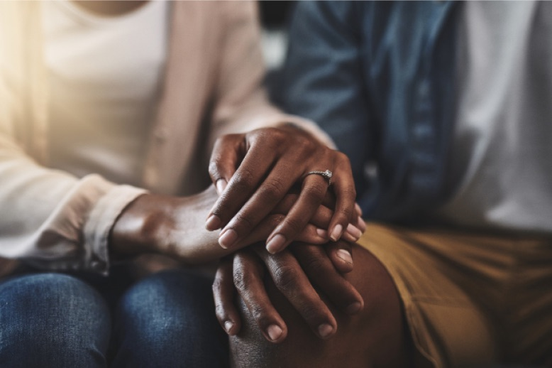 cropped-shot-of-man-and-woman-sitting-on-sofa-holding-hands-in-page