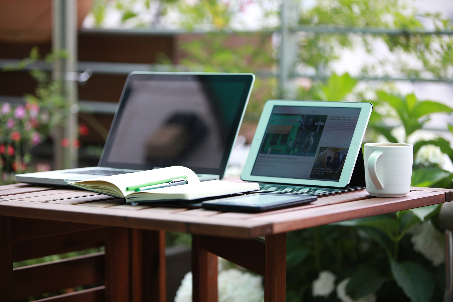 Laptop, tablet, mobile device, and notebook on a desk.