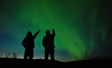 Two people pointing at the Northern Lights