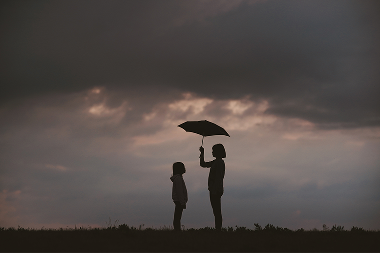 Two children standing underneath an umbrella