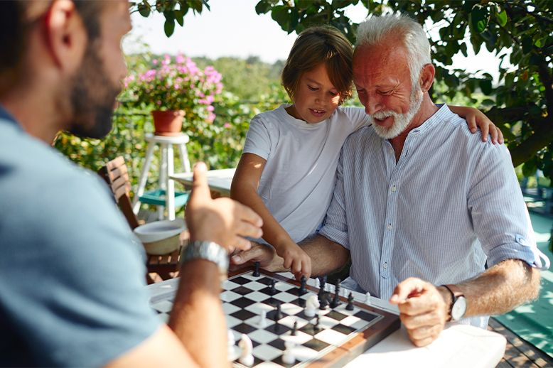three generations of male family playing chess together