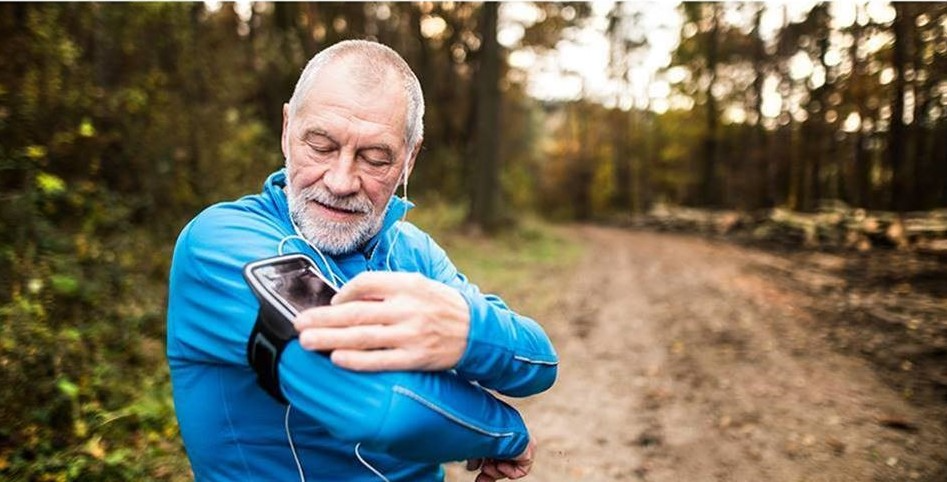 Senior male checking his mobile technology before exercising outdoors.