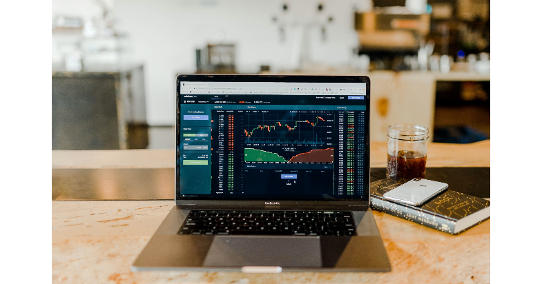 Laptop on a desk. The laptop screen shows a graph.
