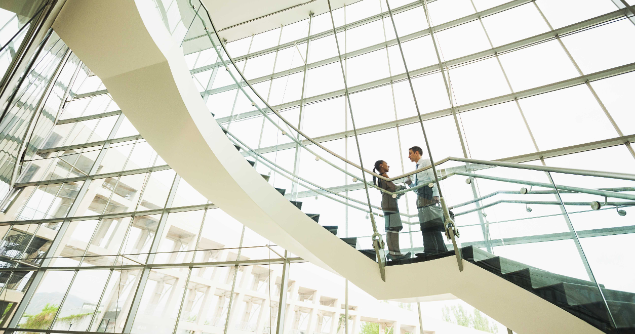 Business people talking on an open staircase in an office building.