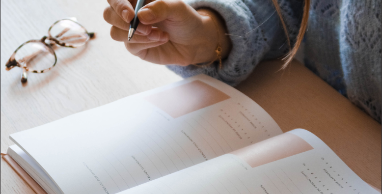 writing in a notebook with pen and glasses