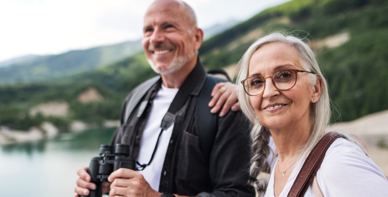 man and woman with mountains and binoculars