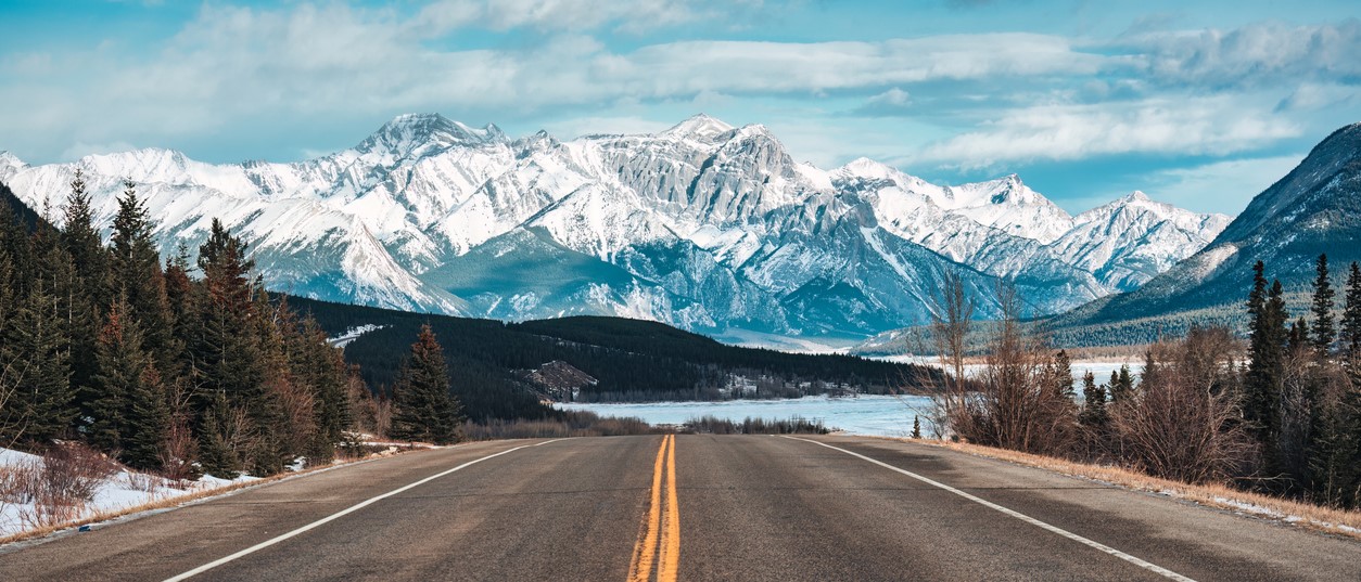 Road trip with on highway road with snow covered rocky mountains in winter