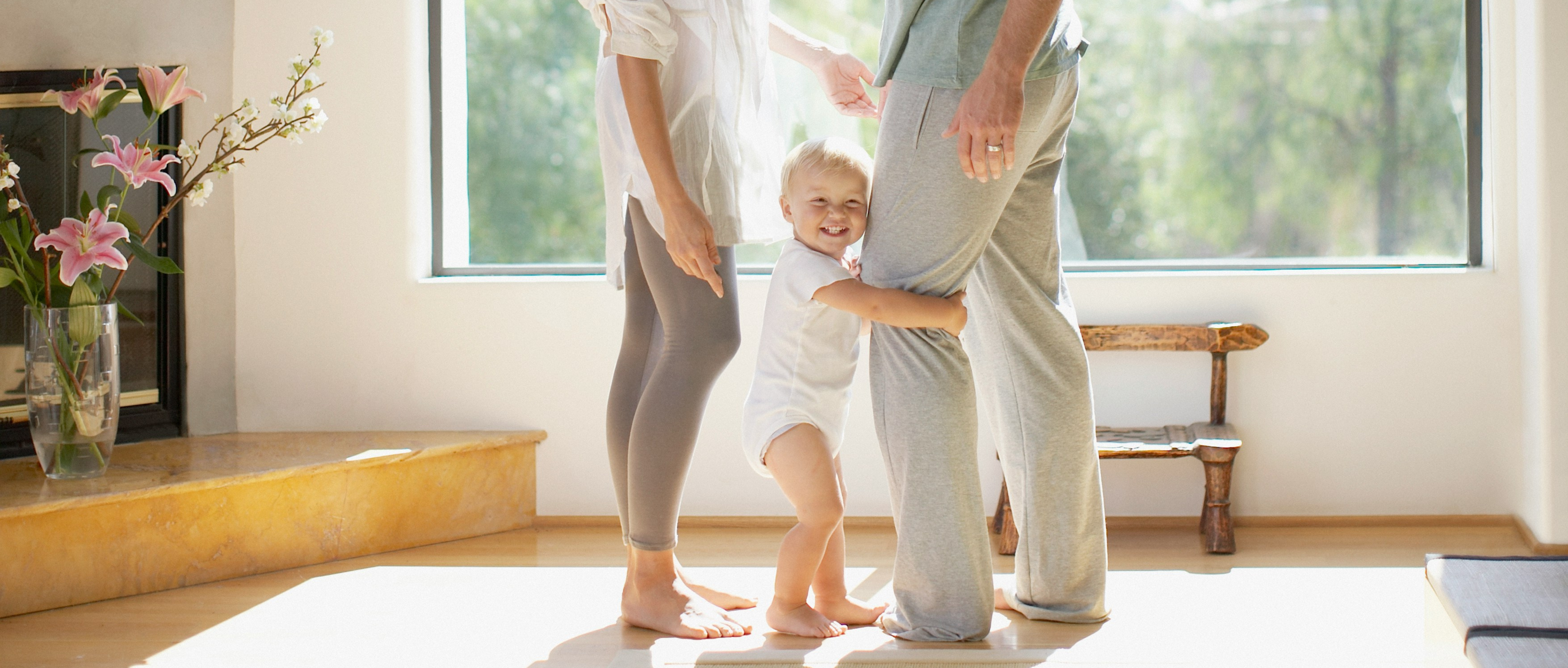 parents looking down a toddler clinging to fathers leg