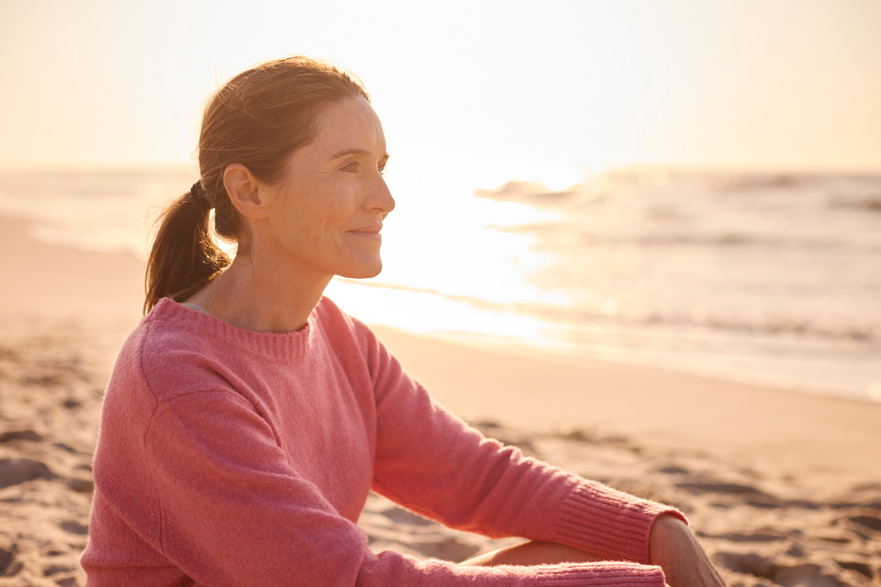 woman sitting on the beach, reflecting