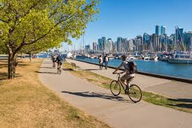 man on bike, riding the sea wall, with the city views behind him