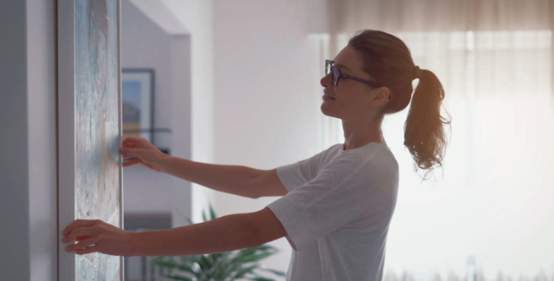 Woman hanging a painting in her home