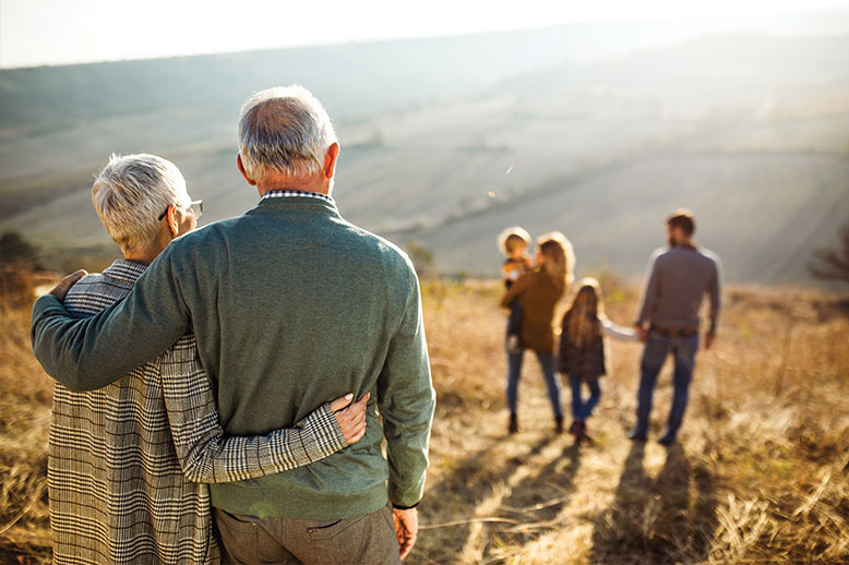 elderly couple embracing watching family in a field