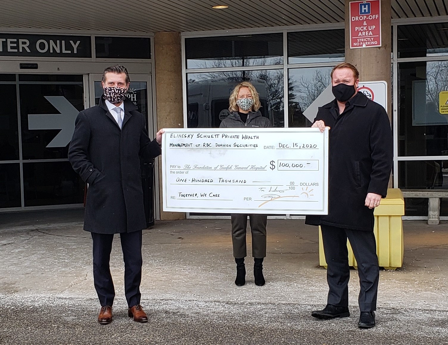 Cheque presentation: Jay Elinesky and Tom Schuett presenting Susanne Bone with an oversize cheque for $100,000. The group is standing in front of the main entrance at Guelph General hospital. All people in the photo are wearing face masks and social distancing. 