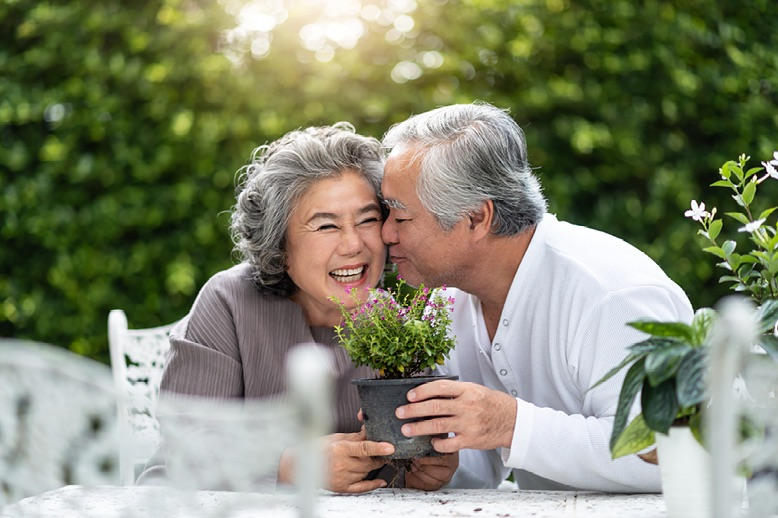 Two seniors sitting at a table holding a potted plant