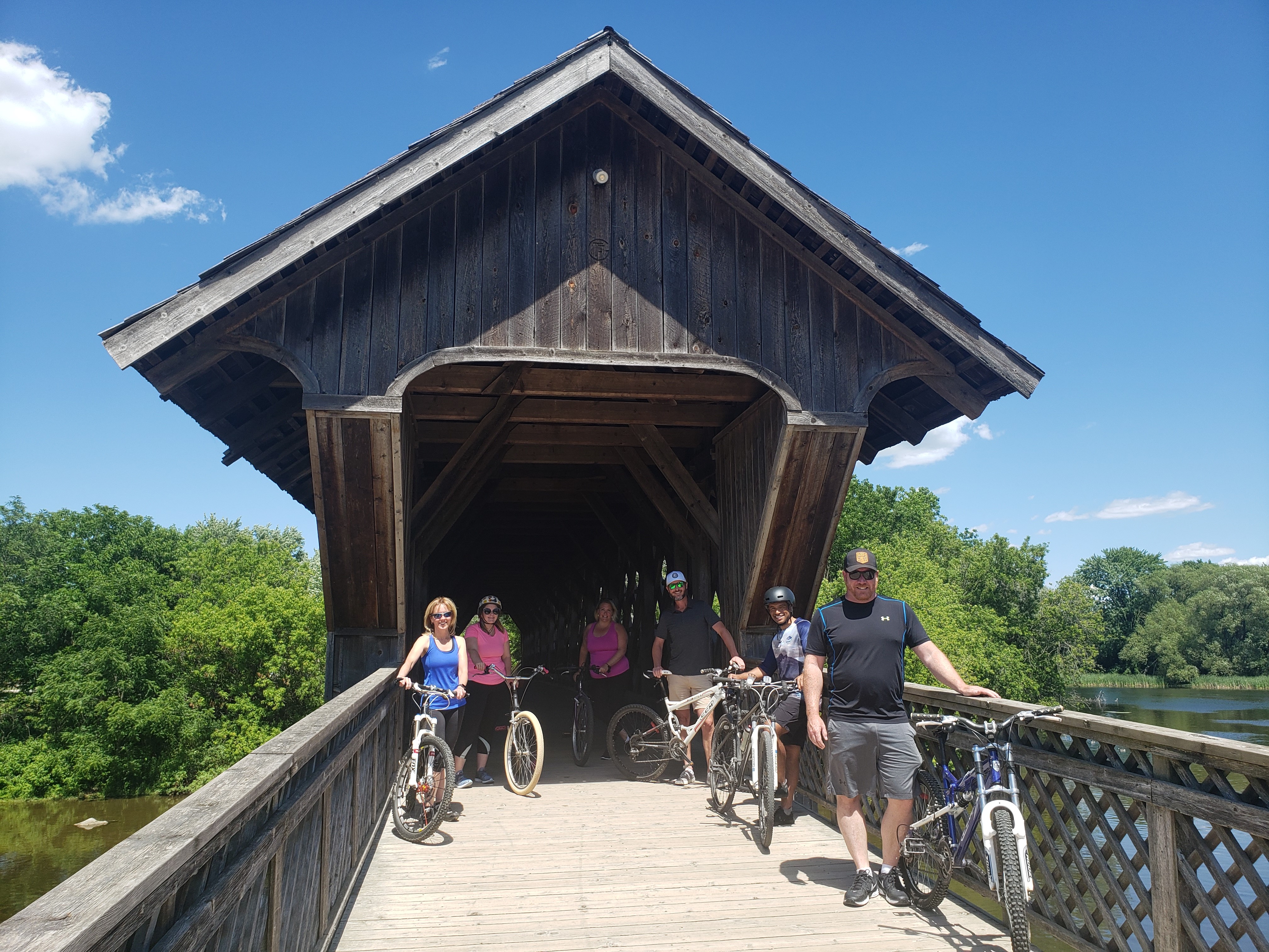 Group of adults standing beside their bikes at a covered bridge