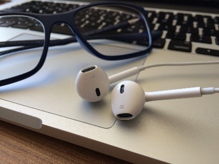 Earbuds and glasses on a laptop keyboard. 