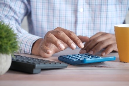 Close-up of man's hands typing on a calculator