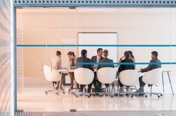 people in office behind glass window.