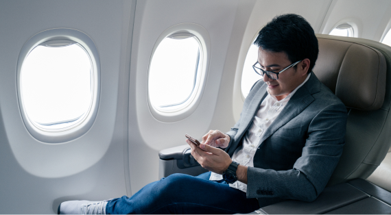 Man seated on plane looking at his phone.