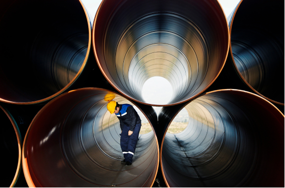Man in stack of large construction pipes
