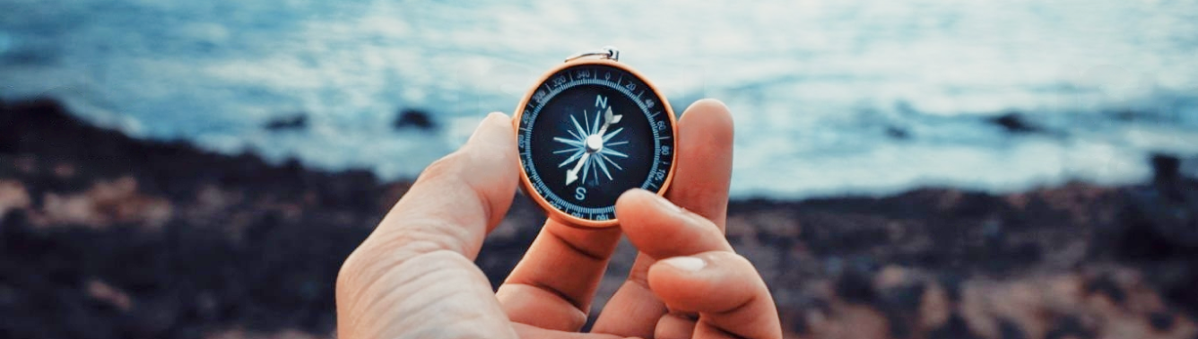 A hand holding a compass.