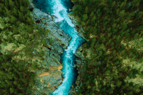 A river surrounded by trees and mountains, as seen from above.
