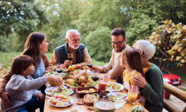 A family gathered around an outdoor dinner table.