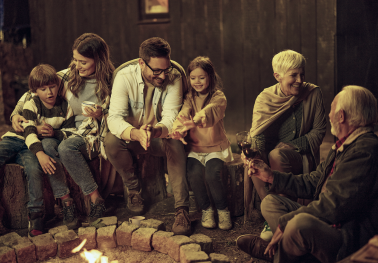 A multigenerational family gathered around a fire.