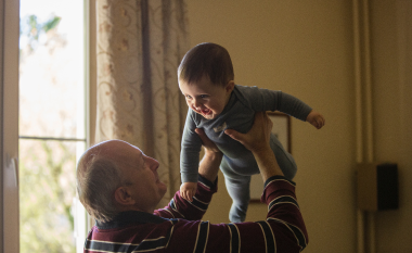 Grandfather holding child in the air. 