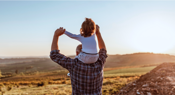 A grandfather carrying his grandchild on his shoulders.