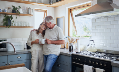 Clients hugging in their kitchen as they share a cup of coffee.