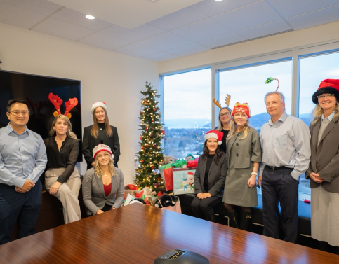 The Hymers Private Wealth team posing beside gifts under a Christmas tree.