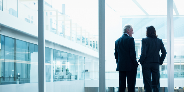 Deux personnes debout près d’une fenêtre de bureau.