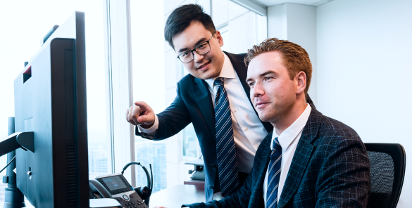 Two members of the Rae Family Wealth team looking at a monitor.