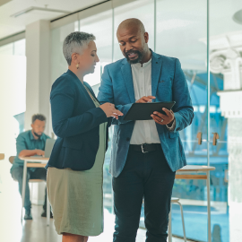 Two people looking at a tablet in an office.