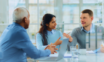 Three people talking around an office table.