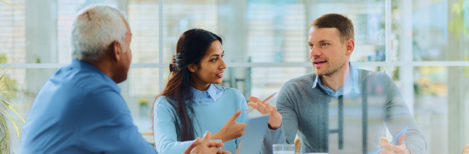 Three people talking around an office table.