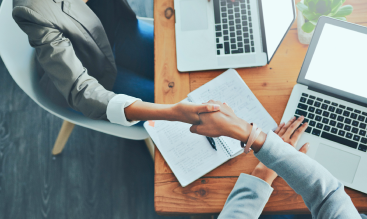 Two people shaking hands in an office.