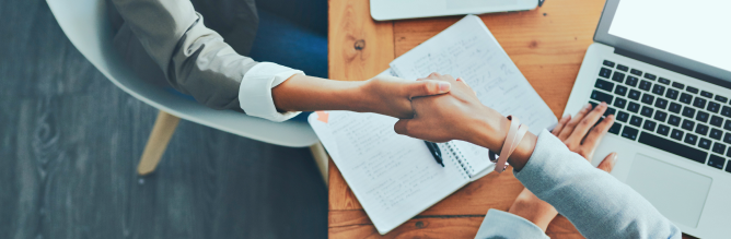 Two people shaking hands in an office.