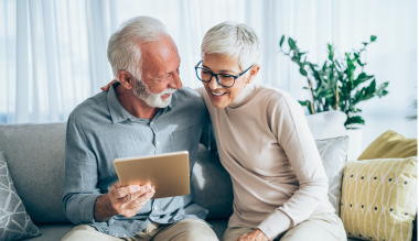 An elderly couple examining a tablet.