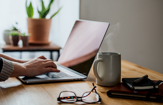Person working on a laptop with a cup of coffee.