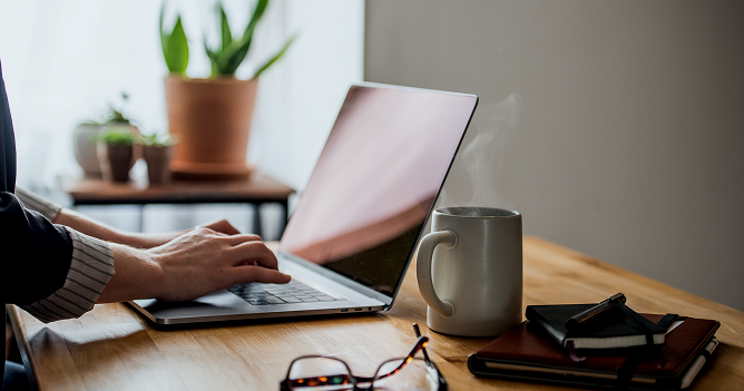 Person working on a laptop with a cup of coffee.