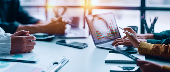 People discussing graphs on a laptop screen.