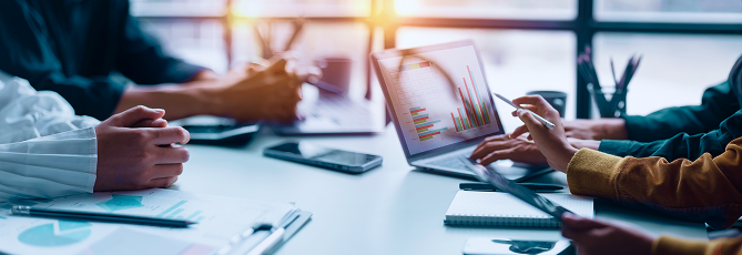 People discussing graphs on a laptop screen.