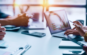 People discussing graphs on a laptop screen.